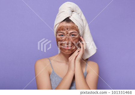 Indoor studio picture of pleasant peaceful sweet female with towel on head, having mask on face, caring about her beauty, spa day, enjoying procedures, staying alone. People and skin care concept. 101331468