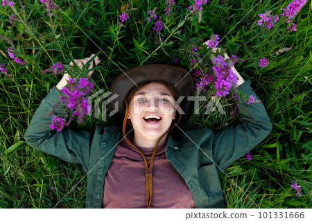 Funny woman lying in summer grass and purple flowers. Wellness. Hello summer. Top view. Summertime. Young woman 20s years smiling. Happy youth. Out of focus Funny woman lying in summer grass and purple flowers. Wellness. Hello summer. Top view. Summertime. Young woman 20s years smiling. Happy youth. Out of focus 101331666