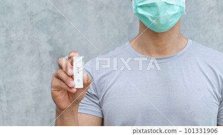Man holding antigen test kit on a gray background. Man holding antigen test kit on a gray background. 101331906