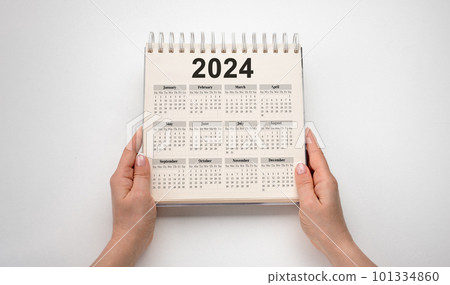 Hands hold Calendar Year 2024 schedule. 2024 desk calender notepad on wooden table and gray background. New Year. plans for 2024. white background 101334860