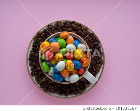 Mug full of color eggs on plate with coffee beans on background with copy space 101335167
