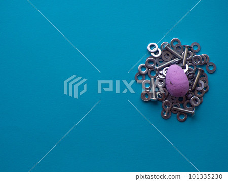 Violet Easter egg on blue background with metal screws 101335230