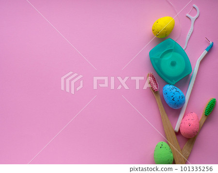 Wooden toothbrushes with Easter decorations on pink background Wooden toothbrushes with Easter decorations on pink background 101335256
