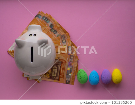 Piggy bank surrounded by colorful Easter eggs on pink background. 101335260