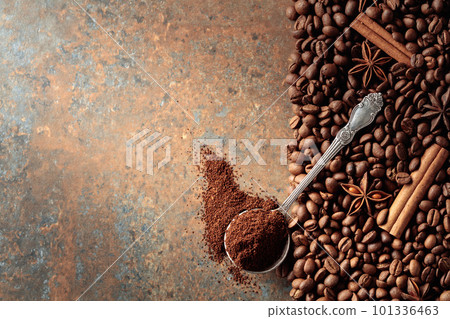 Ground coffee in a spoon and coffee beans with cinnamon and anise on a rusty metal background. 101336463