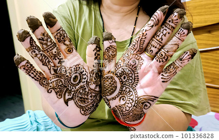 Beautiful artwork drawn on the hand of an Indian bride with herbal heena in wet condition. Beautiful artwork drawn on the hand of an Indian bride with herbal heena in wet condition. 101336828