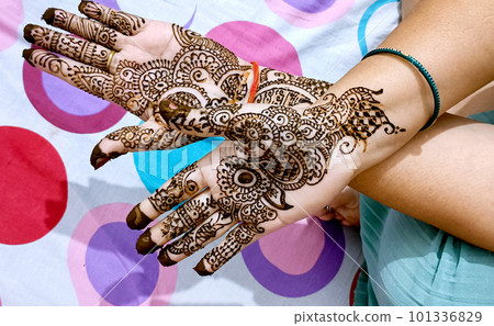 Beautiful artwork drawn on the hand of an Indian bride with herbal heena in wet condition. Beautiful artwork drawn on the hand of an Indian bride with herbal heena in wet condition. 101336829