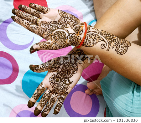 Beautiful artwork drawn on the hand of an Indian bride with herbal heena in wet condition. 101336830