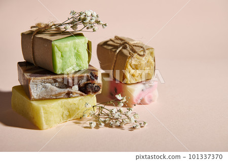 Still life. Bars of organic soap wrapped in eco paper and gypsophila flowers, on isolated beige background. Concept of natural ecological cosmetic products for skin body care with natural ingredients Still life. Bars of organic soap wrapped in eco paper and gypsophila flowers, on isolated beige background. Concept of natural ecological cosmetic products for skin body care with natural ingredients 101337370