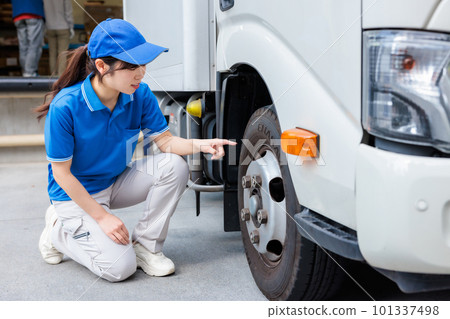 Young female driver performing pre-work inspection of truck Young female driver performing pre-work inspection of truck 101337498