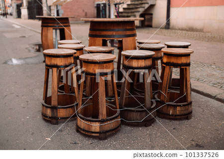 Vintage old wooden wine barrel used as a bar table with two barstools in front of an ancient virgin stone wall in Gdansk, Poland 101337526