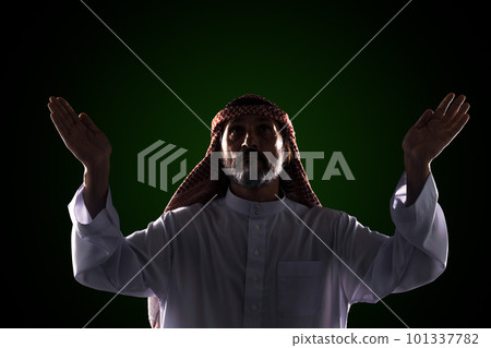 Muslim man raises his hands to sky in prayer and praise, expressing his devotion and faith in One God of Allah. Spirituality and traditional practices of Islamic culture and religion. 101337782
