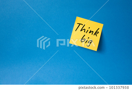 Think big symbol. Orange steaky note with words Think big. Beautiful blue background. Business and Think big concept. Copy space. Think big symbol. Orange steaky note with words Think big. Beautiful blue background. Business and Think big concept. Copy space. 101337938