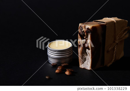 Natural ecological cosmetic products concept. A bar with organic homemade soap with coffee beans and jar with wax, isolated on black background. Skin and body care, spa concept. Copy advertising space 101338229
