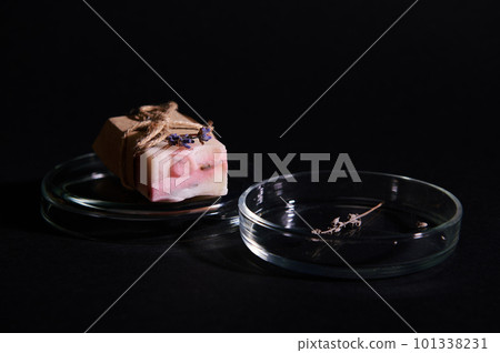 Details on a bar of handmade organic soap of pink marble color with natural ingredients, on petri dish with dry lavender flowers, isolated black background. Skin and body care. Hygiene Purity Home Spa Details on a bar of handmade organic soap of pink marble color with natural ingredients, on petri dish with dry lavender flowers, isolated black background. Skin and body care. Hygiene Purity Home Spa 101338231