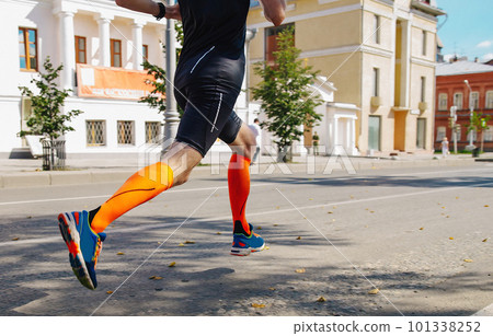 male runner in compression socks running street summer marathon race, endurance sports 101338252