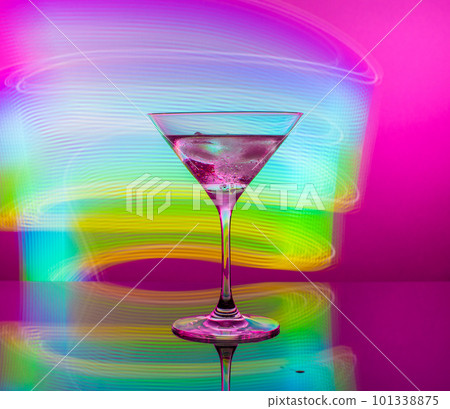 Alcoholic cocktail in a glass goblet against the background of colorful neon lights Alcoholic cocktail in a glass goblet against the background of colorful neon lights 101338875