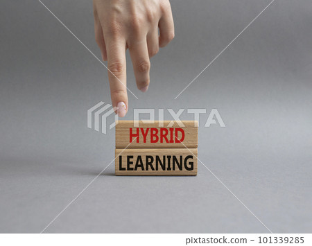 Hybrid learning symbol. Concept word Hybrid learning on wooden blocks. Businessman hand. Beautiful grey background. Business and Hybrid learning concept. Copy space 101339285