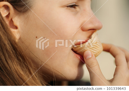 Close up of young girl's face eating waffle cup, side view Close up of young girl's face eating waffle cup, side view 101339643