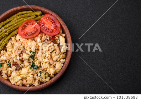 Delicious scramble with salmon, sun-dried tomatoes, spinach, spices and herbs 101339688