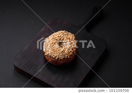 Delicious donut with cream filling and nuts on a dark concrete background 101339700