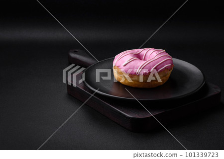 Delicious donut with cream filling and nuts on a dark concrete background Delicious donut with cream filling and nuts on a dark concrete background 101339723