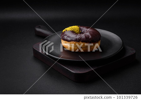 Delicious donut with cream filling and nuts on a dark concrete background Delicious donut with cream filling and nuts on a dark concrete background 101339726
