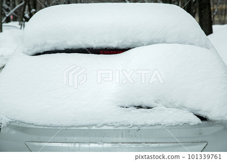 rear window with windshield wiper, washer and brake light covered with a large layer of snow on a winter cold day. rear window with windshield wiper, washer and brake light covered with a large layer of snow on a winter cold day. 101339761