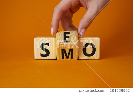 SEO vs SMO symbol. Businessman hand turns wooden cubes and changes the word SMO to SEO. Beautiful orange background. SEO vs SMO and business concept. Copy space SEO vs SMO symbol. Businessman hand turns wooden cubes and changes the word SMO to SEO. Beautiful orange background. SEO vs SMO and business concept. Copy space 101339992