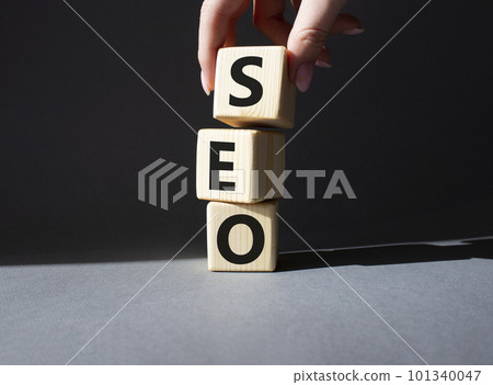 SEO - Search Engine Optimization symbol. Wooden blocks with words SEO. Businessman hand. Beautiful grey background. Business and SEO concept. Copy space. 101340047
