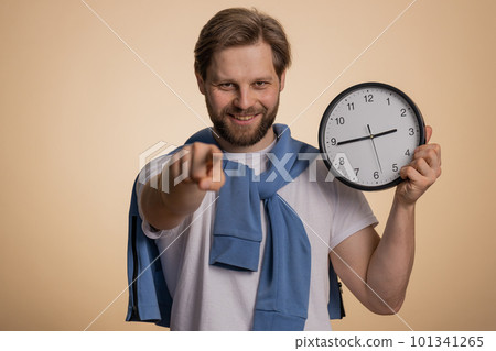 Smiling man showing time on wall office clock, ok, thumb up, approve, pointing finger at camera 101341265