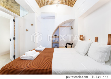 Traditional modern Iberian bedroom with brick ceiling and clean towels and linens. Traditional modern Iberian bedroom with brick ceiling and clean towels and linens. 101341534