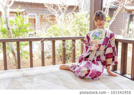 A young woman in a yukata relaxing on the porch 101342958