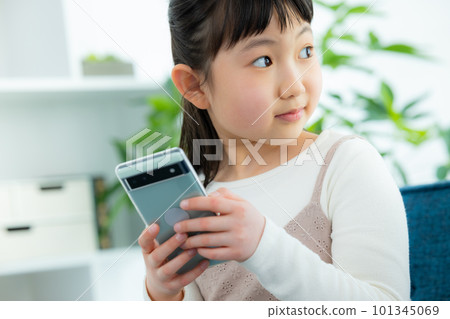 A child looking at a smartphone in the living room　 101345069