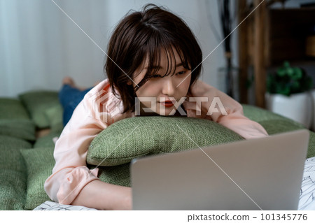 Young woman lying down and using a laptop 101345776