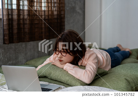 Young woman lying down and using a laptop Young woman lying down and using a laptop 101345782