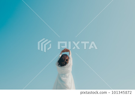 A woman holding her hand against the blue sky background 101345872
