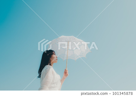 藍天背景中拿著遮陽傘的女人 藍天背景中拿著遮陽傘的女人 101345878
