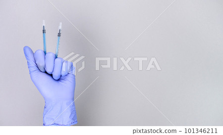 Hand in blue gloves of doctor or nurse holding syringe with liquid vaccine over grey background with copy space. New vaccine. Unknown vaccine. Medical gloves. 101346211