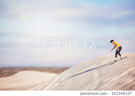 Sandboard, desert and mockup with a sports man outdoor on the sand dunes for recreation, fun or adventure. Sky, nature and mock up with a male athlete or sandboarding moving downhill at speed 101348187