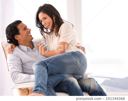 Shes in a playful mood...A loving wife sitting on her husbands lap in the living room. Shes in a playful mood...A loving wife sitting on her husbands lap in the living room. 101348366