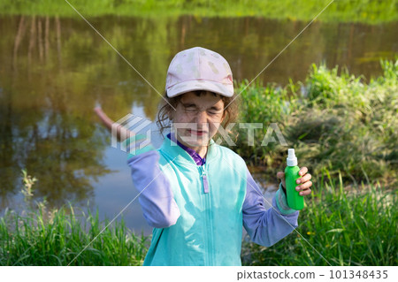 Girl sprays mosquito spray on the skin in nature that bite her hands and feet. Protection from insect bites, repellent safe for children. Outdoor recreation, against allergies. Summer time Girl sprays mosquito spray on the skin in nature that bite her hands and feet. Protection from insect bites, repellent safe for children. Outdoor recreation, against allergies. Summer time 101348435