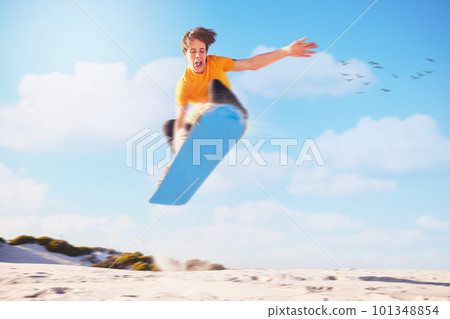 Sport, sandboard man jumping man in a desert for extreme sports, fitness and training against blue sky background. Sandboarding, jump and guy in dunes with energy, freedom and adrenaline in Dubai 101348854