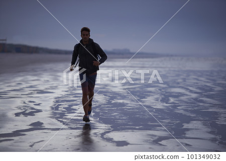 Starting the day with a jog on the beach. A young man jogging on the beach in the early morning. Starting the day with a jog on the beach. A young man jogging on the beach in the early morning. 101349032