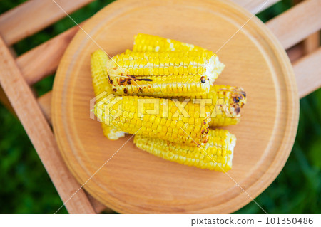 Delicious, sweet young grilled popcorn lies on a wooden board, outdoor recreation, proper nutrition. Delicious, sweet young grilled popcorn lies on a wooden board, outdoor recreation, proper nutrition. 101350486
