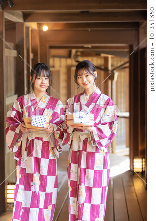 A young woman walking down the connecting corridor of a ryokan and heading to a hot spring 101351350