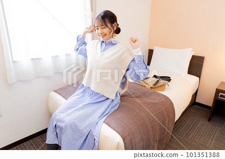 入住後坐在房間床上的年輕女子 入住後坐在房間床上的年輕女子 101351388