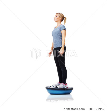 Shes getting a full-body workout. An attractive young woman working her core muscles by balancing on a bosu-ball. Shes getting a full-body workout. An attractive young woman working her core muscles by balancing on a bosu-ball. 101351952