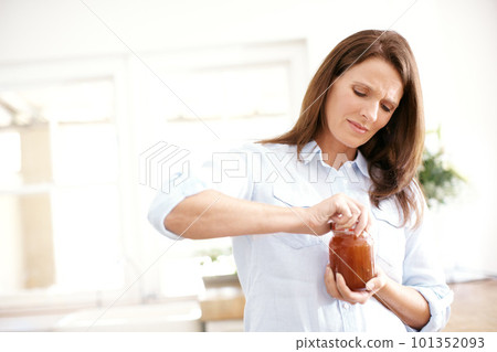 Its too tight. A mature woman trying to open a jar in the kitchen. 101352093