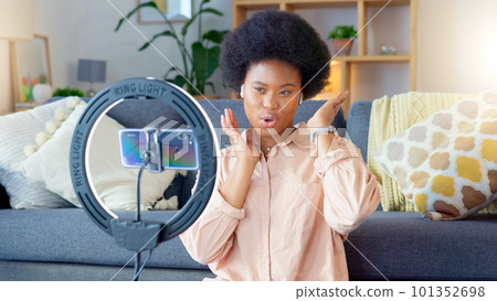 Female influencer and vlogger recording content on a phone at home. Young creator live streaming online for a vlog channel. Filming a podcast while speaking to followers and viewers on social media 101352698